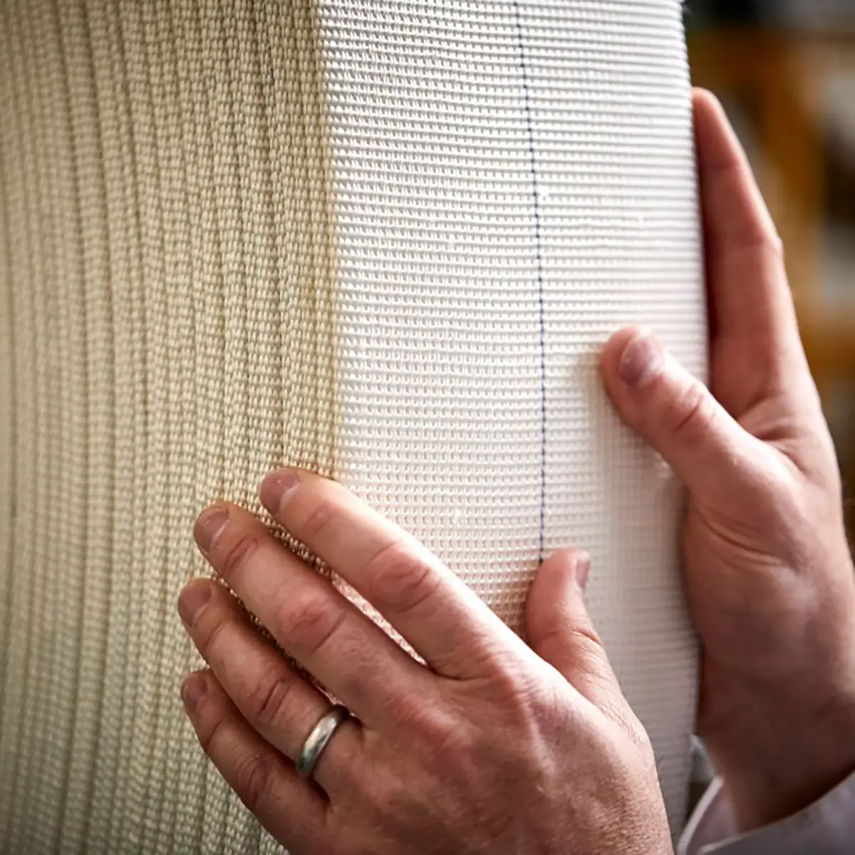 Contrôle qualité bande haute densité Mains effectuant un contrôle qualité sur une bande textile haute densité épaisse blanche avec ligne de repère bleue